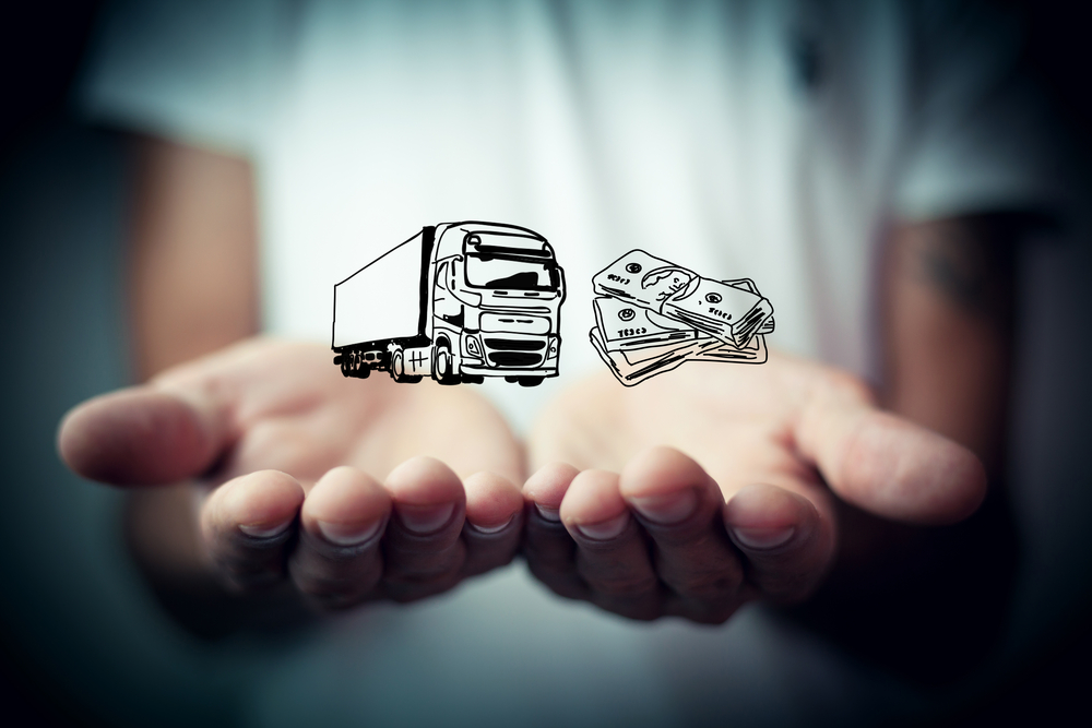 Freight truck symbol held up next to a symbol of money