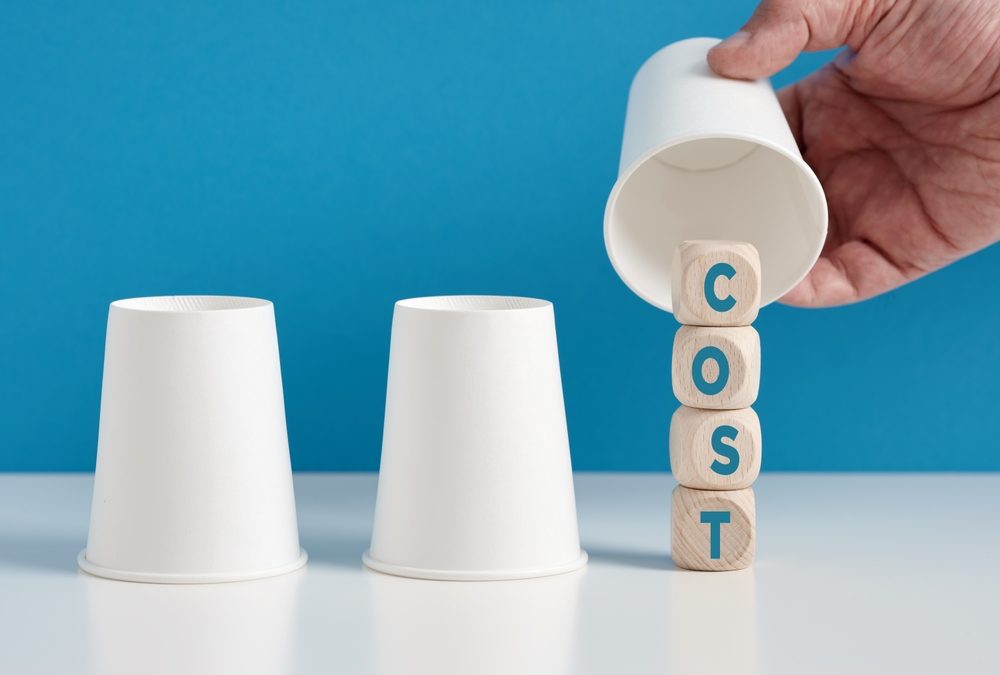 Blocks stacked vertically to say the word "cost" being covered by a paper cup
