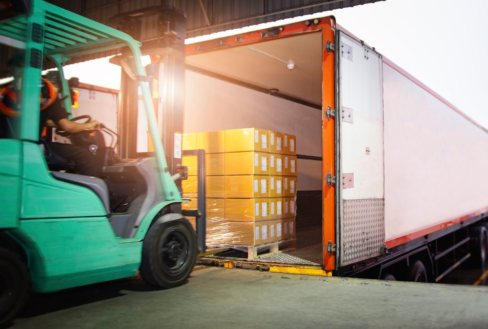 Forklift loading a freight trucking with packages.