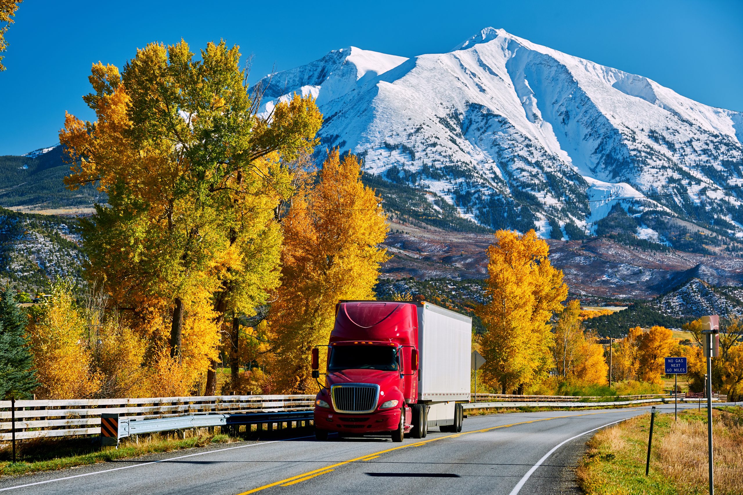 red freight truck on highway with mountains in background in Colorado