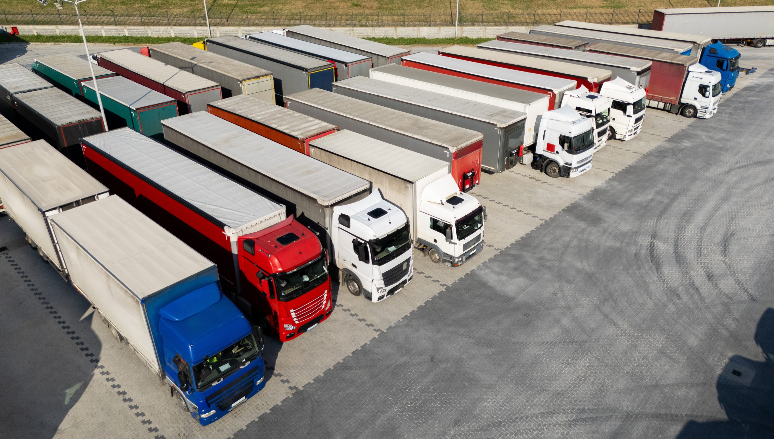line of large semi-trucks lined up to load freight at a port