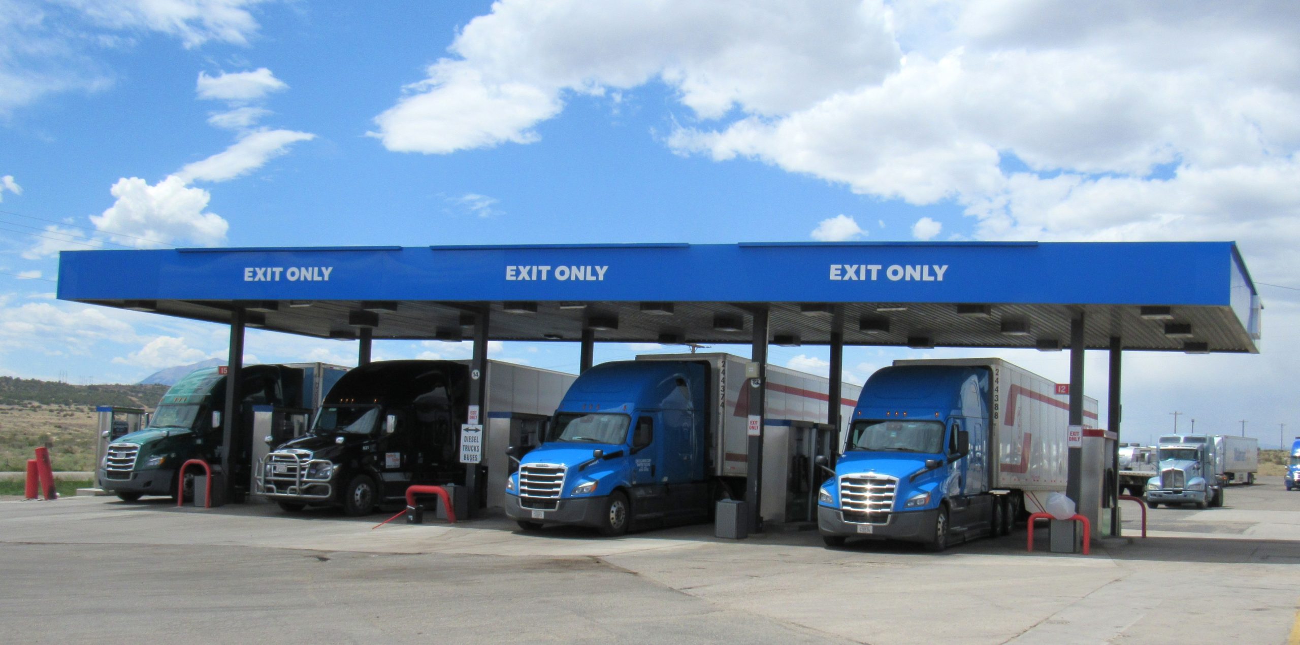 Blue freight trucks lined up getting gas in Walsenburg, Colorado